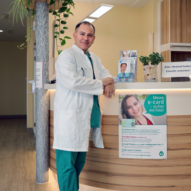 Dr. Babak Bahadori lehnt am Empfangstisch seiner Ordination